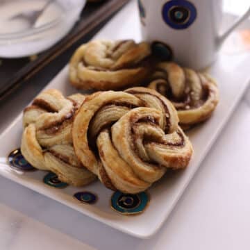 A zoomed in image of cinnamon swirls on a whie plate.