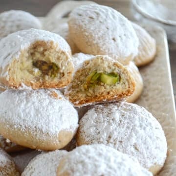 A stack of kahk cookies with one cut in half to show texture.