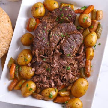 A large platter with beef pot roast and vegetables.