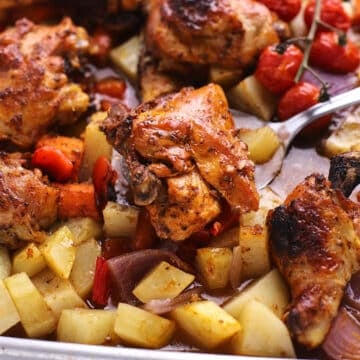 A serving spoon scooping some chicken from the sheet pan.