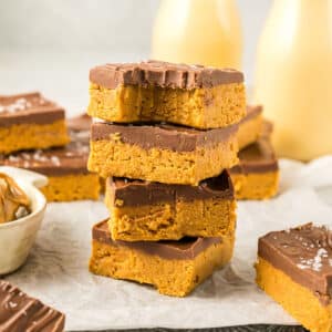 A stack of peanut butter bars with a bite taken from one.