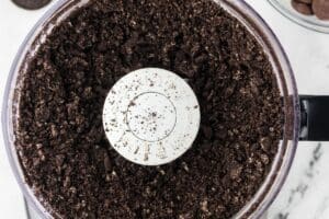 A food processor with crushed oreo cookies.