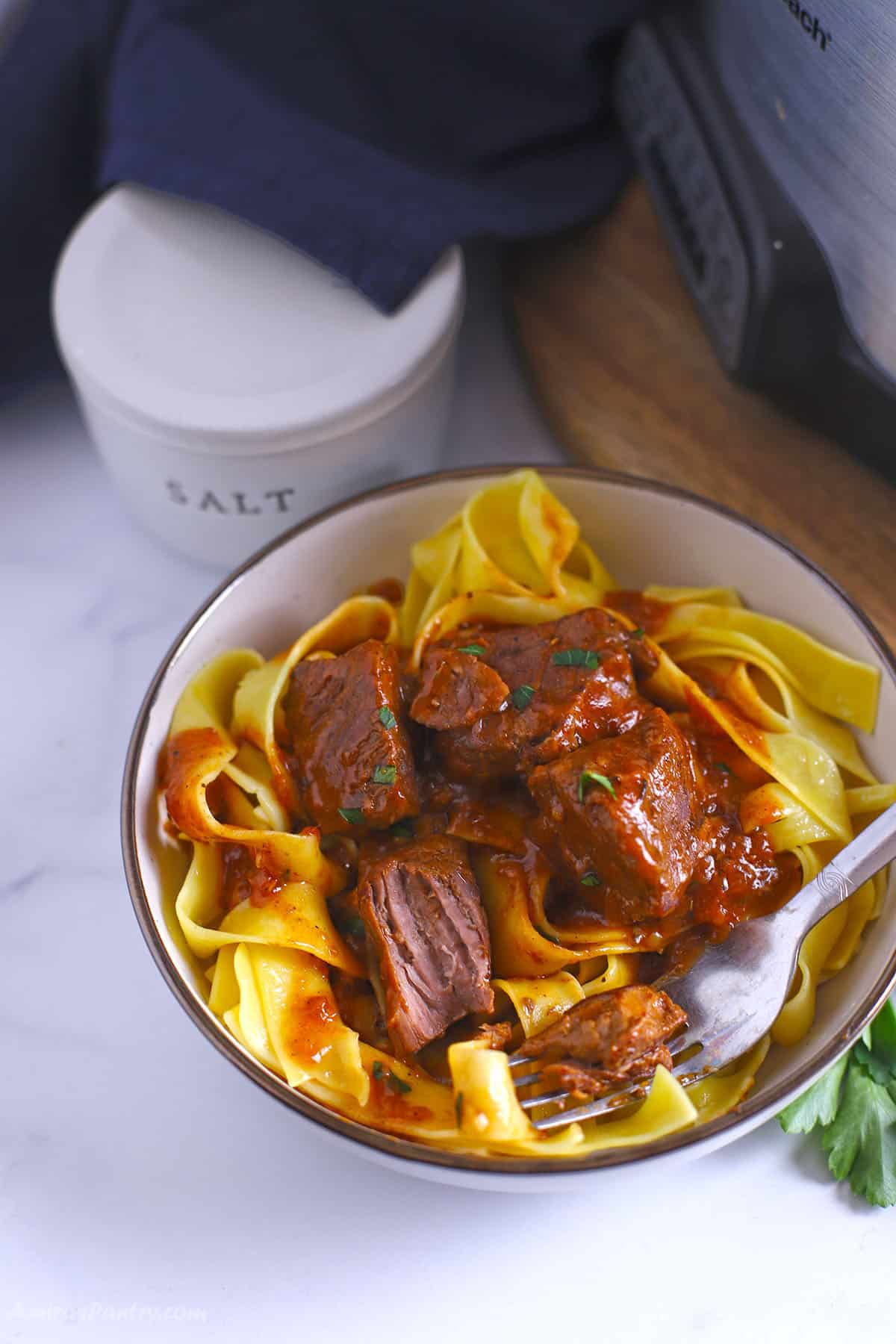 A close up image of a bowl with beef and noodles.