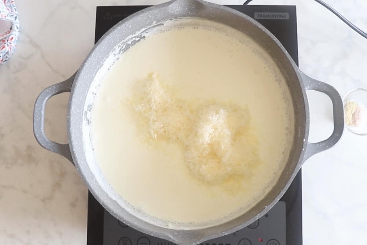 A large skillet with alfredo ingredients topped with parmesan cheese.
