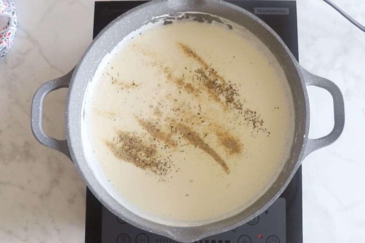 Adding seasoning to the alfredo sauce.