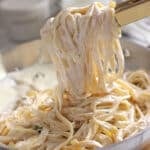 Kitchen tongs with alfredo pasta.