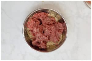 A large bowl with meatballs ingredients mixed.
