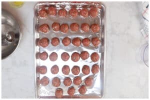 Shaped meatballs on a foil lined baking sheet.