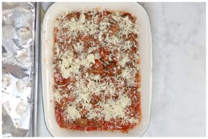Meatballs on a baking dish with marinara sauce and topped with cheese.