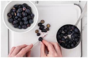 Cutting blueberries in half.