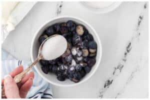 Adding sugar to blueberries.