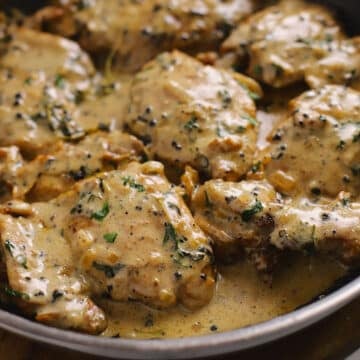 A large skillet with chicken au poivre garnished with parsley.