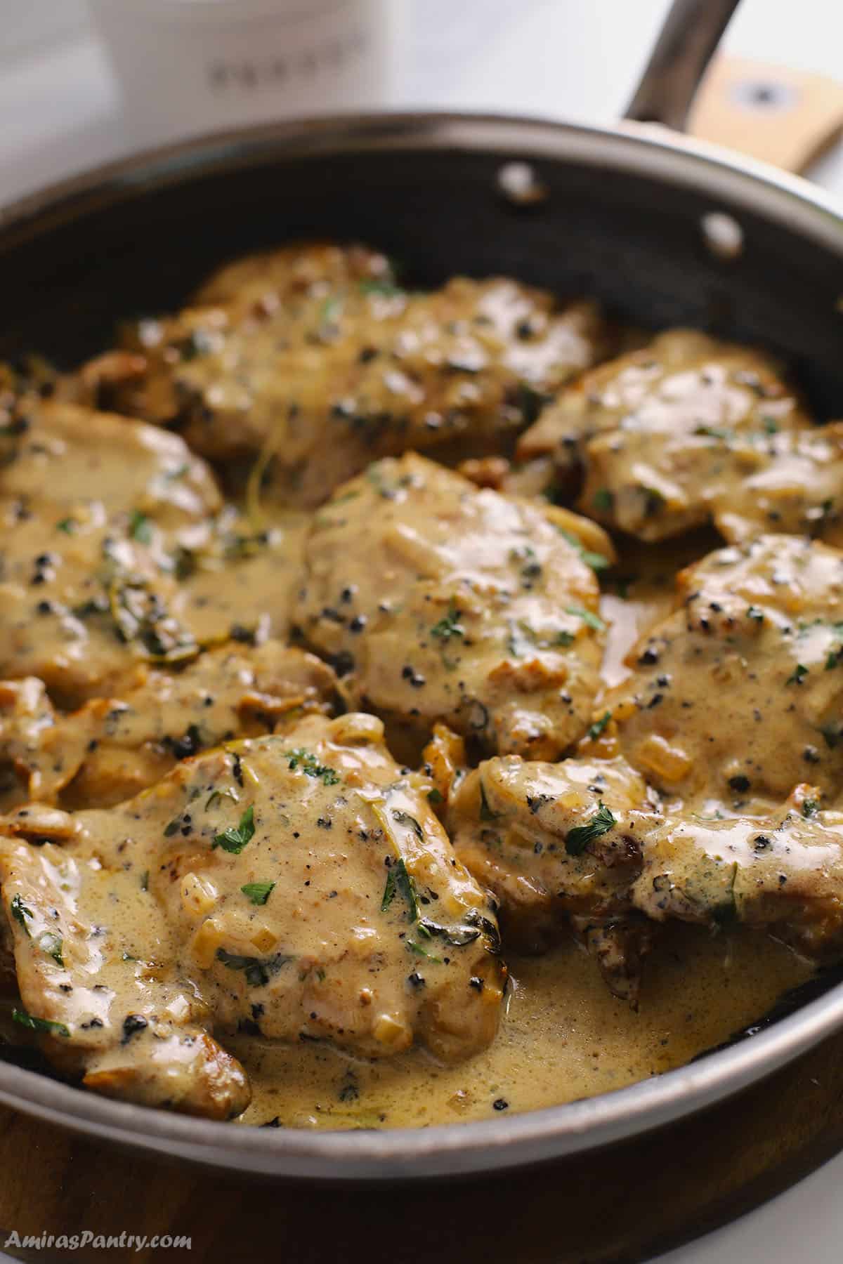 Saucy chicken au poivre in a large skillet garnished with parsley.