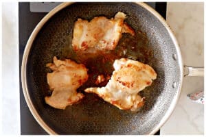 Searing chicken thighs in a large skillet.