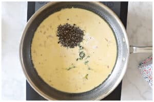 A large skillet with cream sauce, crushed peppercorn and fresh thyme.
