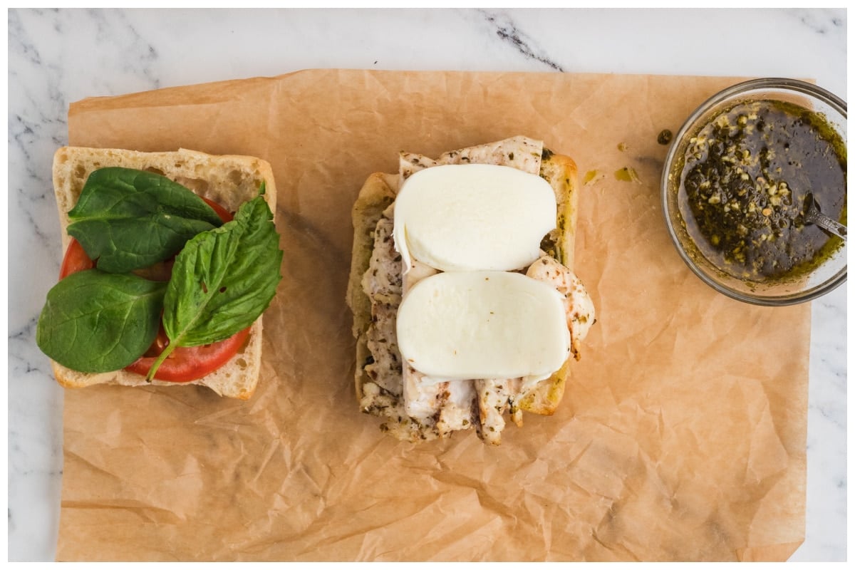 Parchment paper with two halves of crusty bread with sandwich ingredients.