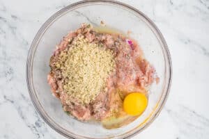 A glass bowl with panko breadcrumbs and eggs added to thhe ground chicken mix.