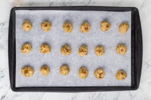 Baked chicken meatballs on a baking sheet lined with parchment paper.
