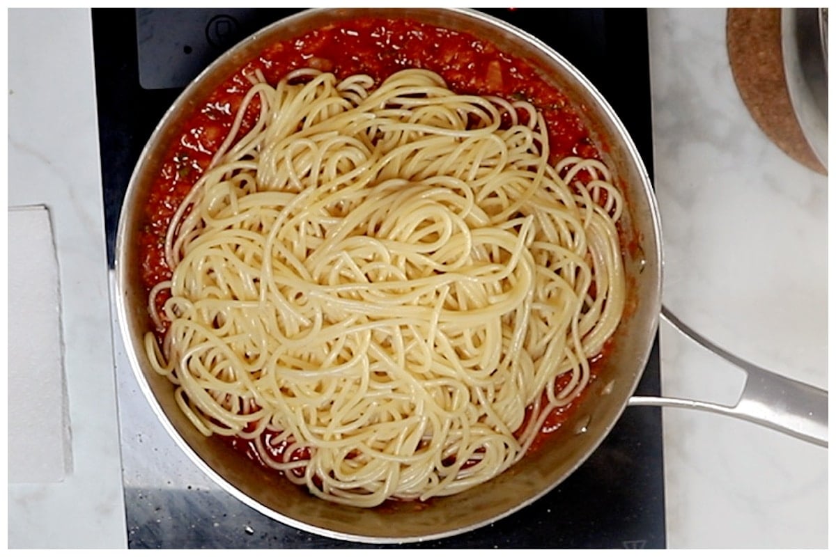 Pasta is added to the skillet with tomato sauce.