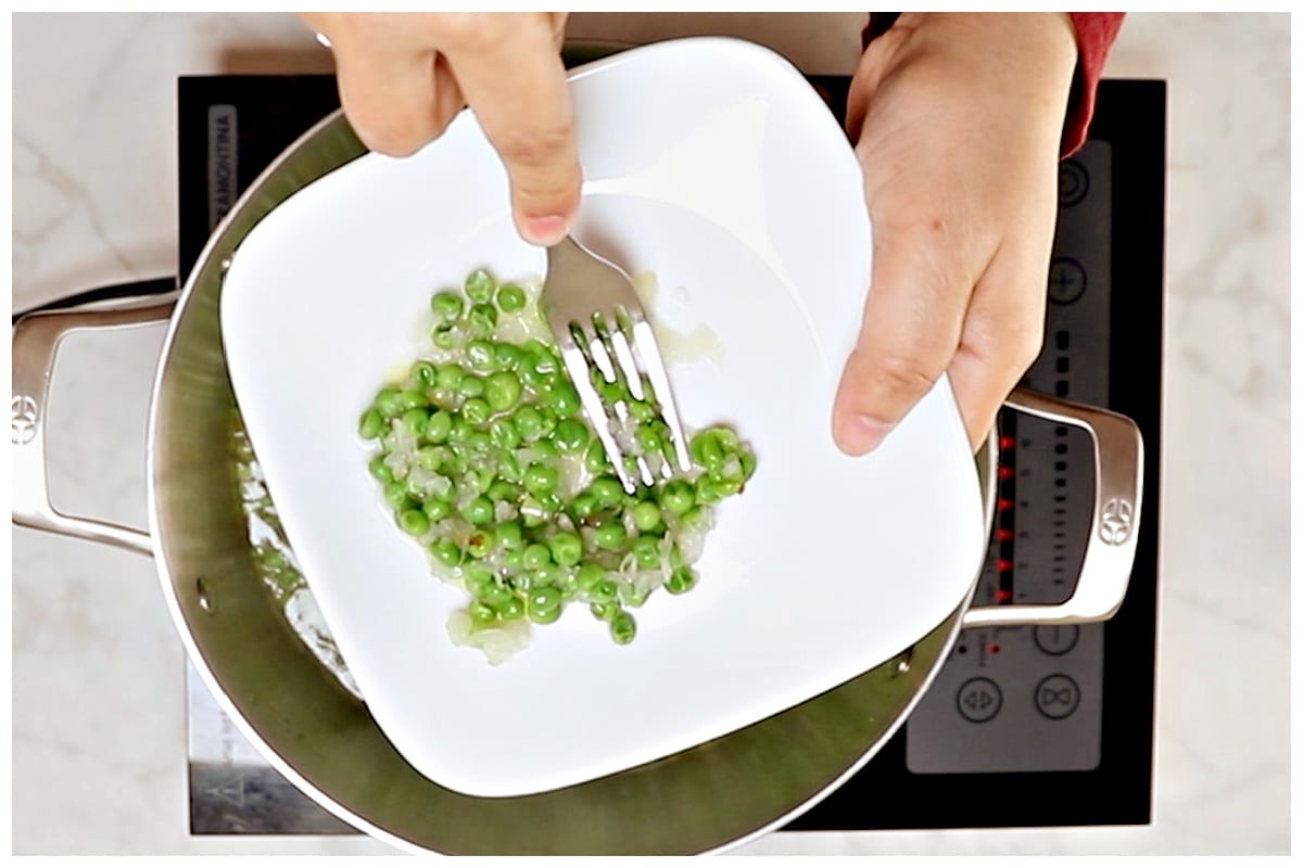 Smashing peas with a fork.