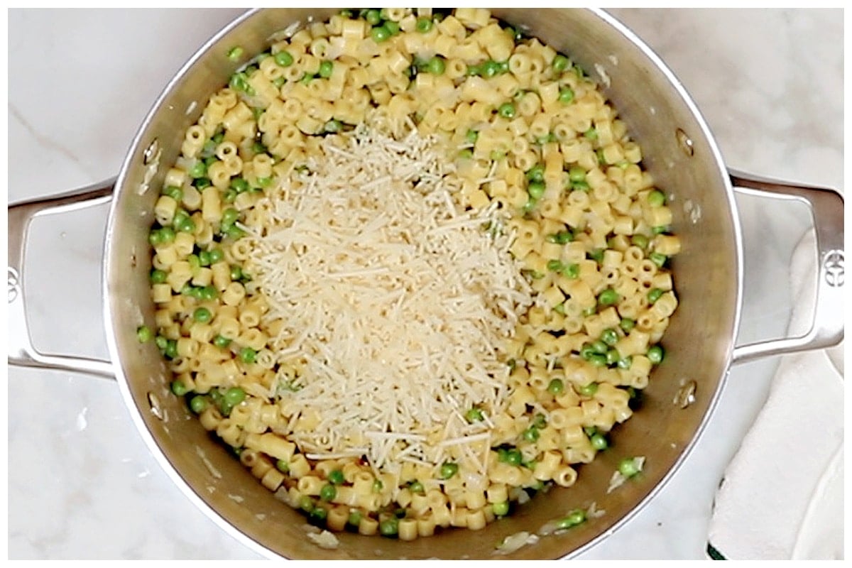 A large pot of pasta and peas topped with grated parmesan cheese.
