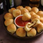 Pizza balls on a platter with cut open to show melty cheese.