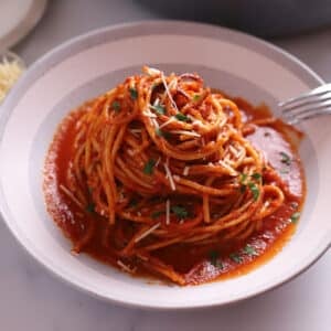 Spaghetti in a big bowl garnished with parsley.