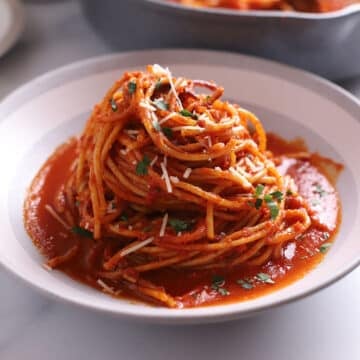 A grey bowl of spaghetti all'assassina with sauce over.
