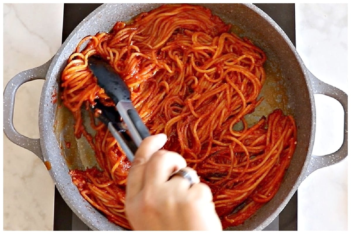Turning spaghetti using tongs.