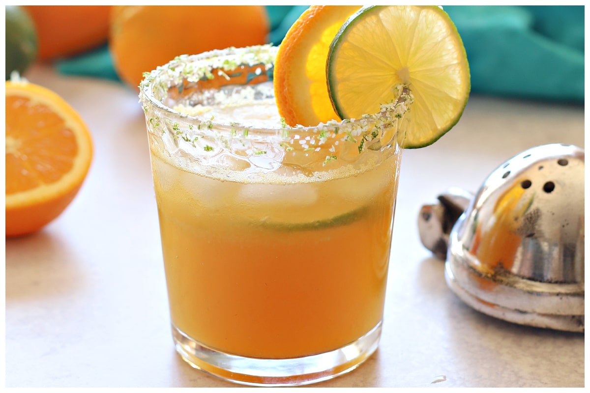 Margarita mocktail in a glass with lime and orange on the back.