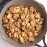 A large skillet with cooked chicken thigs in garlic butter sauce.