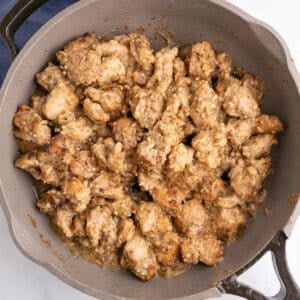 A large skillet with cooked chicken thigs in garlic butter sauce.