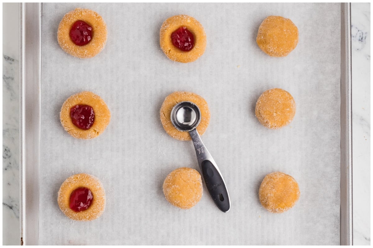 Raw cookies on a cookie sheet filled with jam.