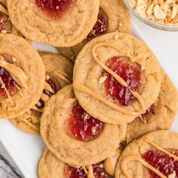 An overhead image of some peanut butter and jam cookies on a serving platter.