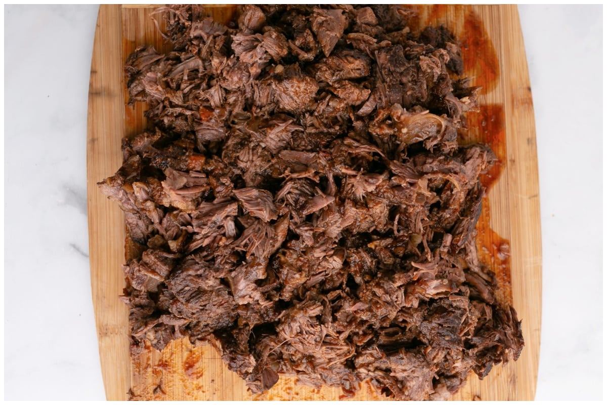 Beef shredded on a wooden cutting board.