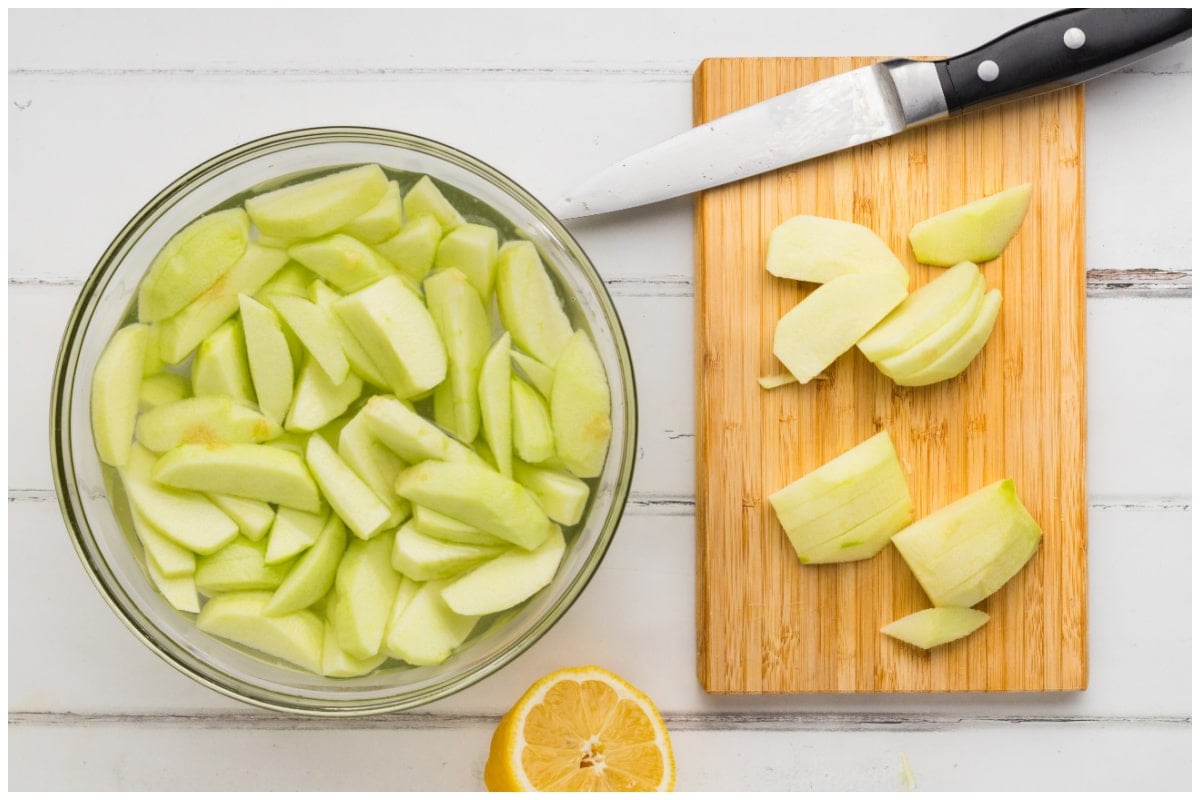 Sliced apples in a large bowl and a wooden board with cut up apples on the side.