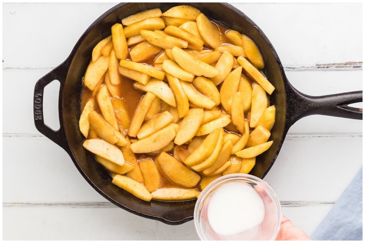 Adding cornstarch mixture to the cooked apples in the pan.