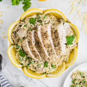 A white bowl of lemon chicken orzo garnished with lemon rings.