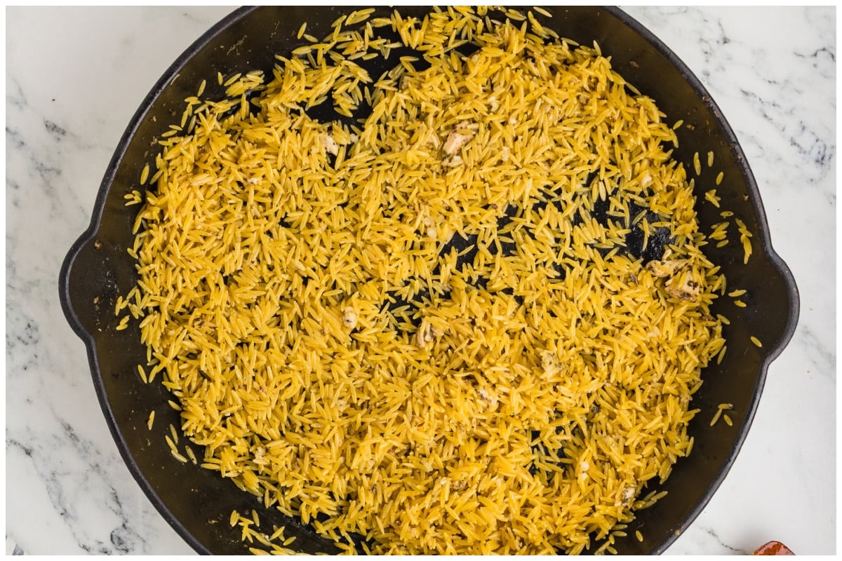 A large skillet with dry orzo.