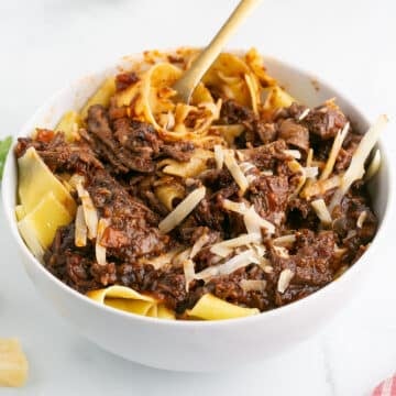 A white bowl of short rib ragu with pasta.