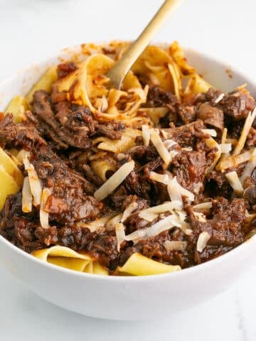 A white bowl of short rib ragu with pasta.