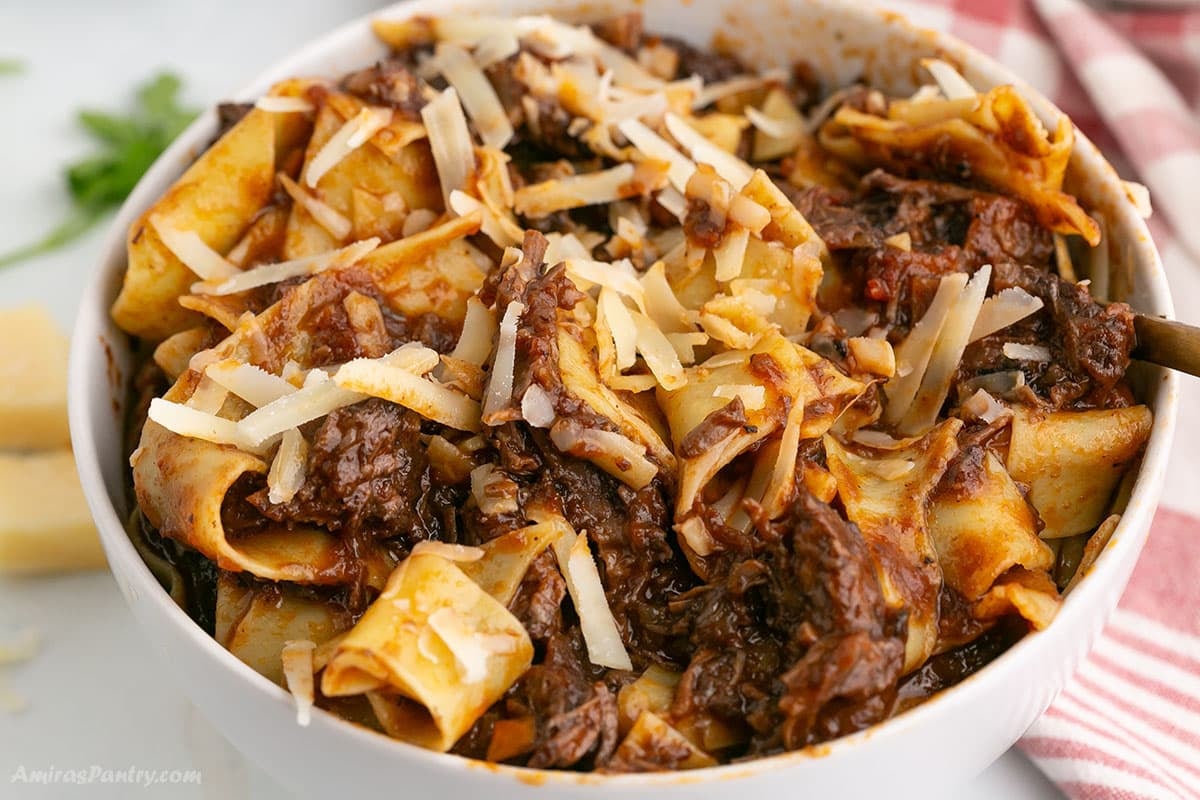 A zoom in image on a bowl of beef ragu served with pasta.