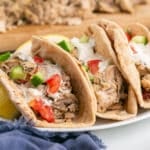 A stack of chicken gyros sandwiches on a platter.