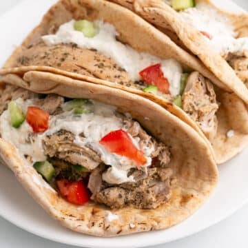 Chicken gyros with white sauce on pita bread.