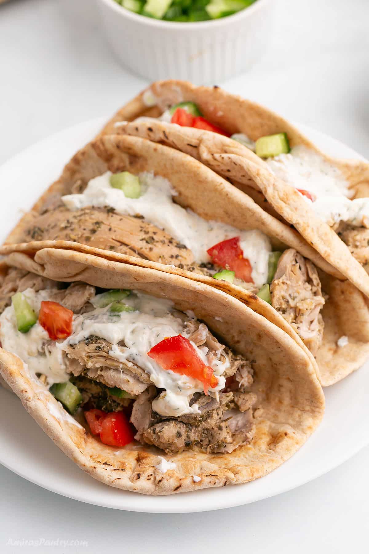 Chicken gyros pitas on a white platter.