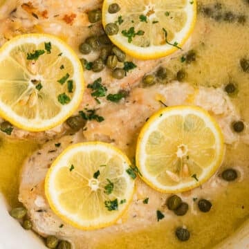 A zoom in image on chicken piccata in a white slow cooker.