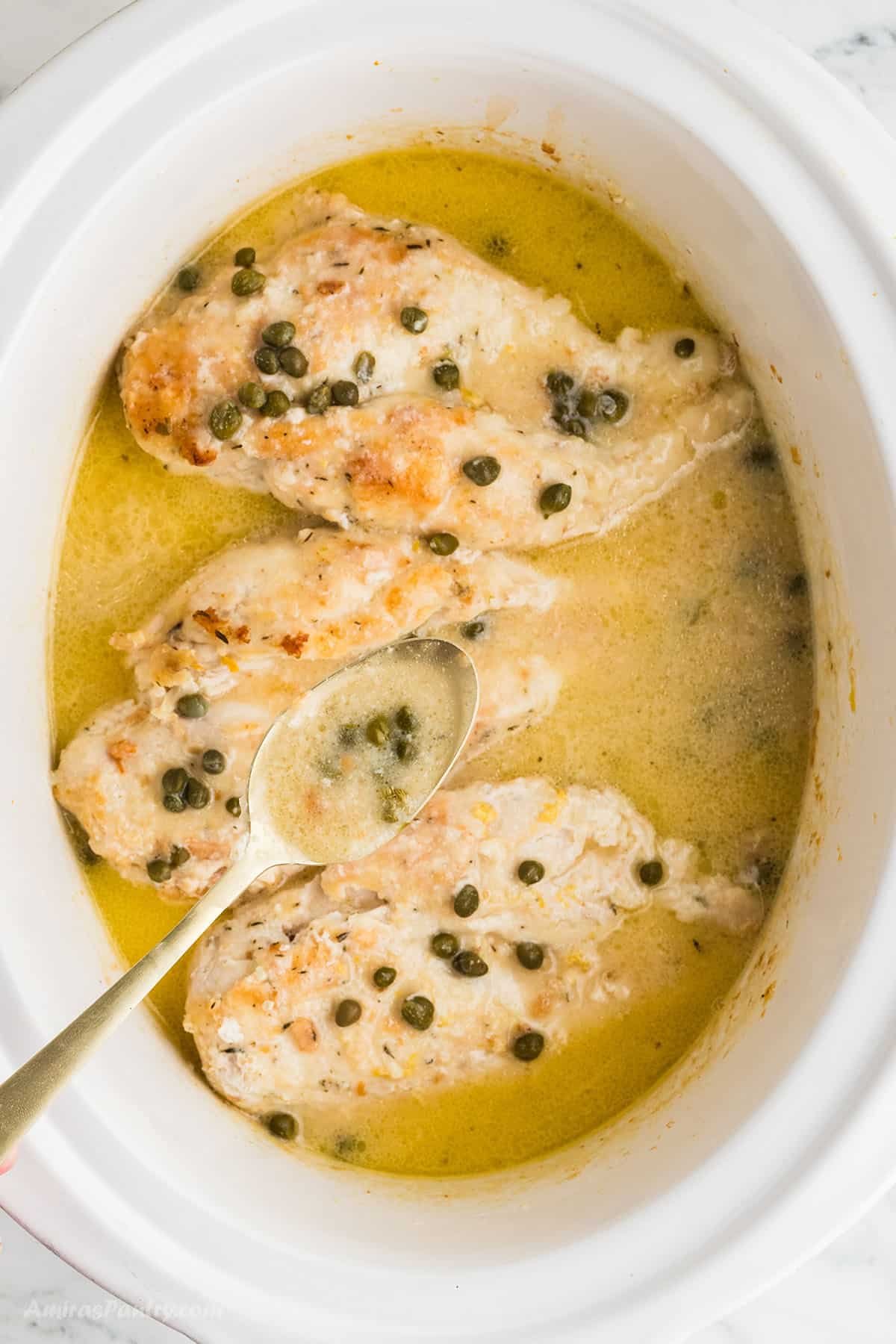 A spoon scooping some piccata sauce.