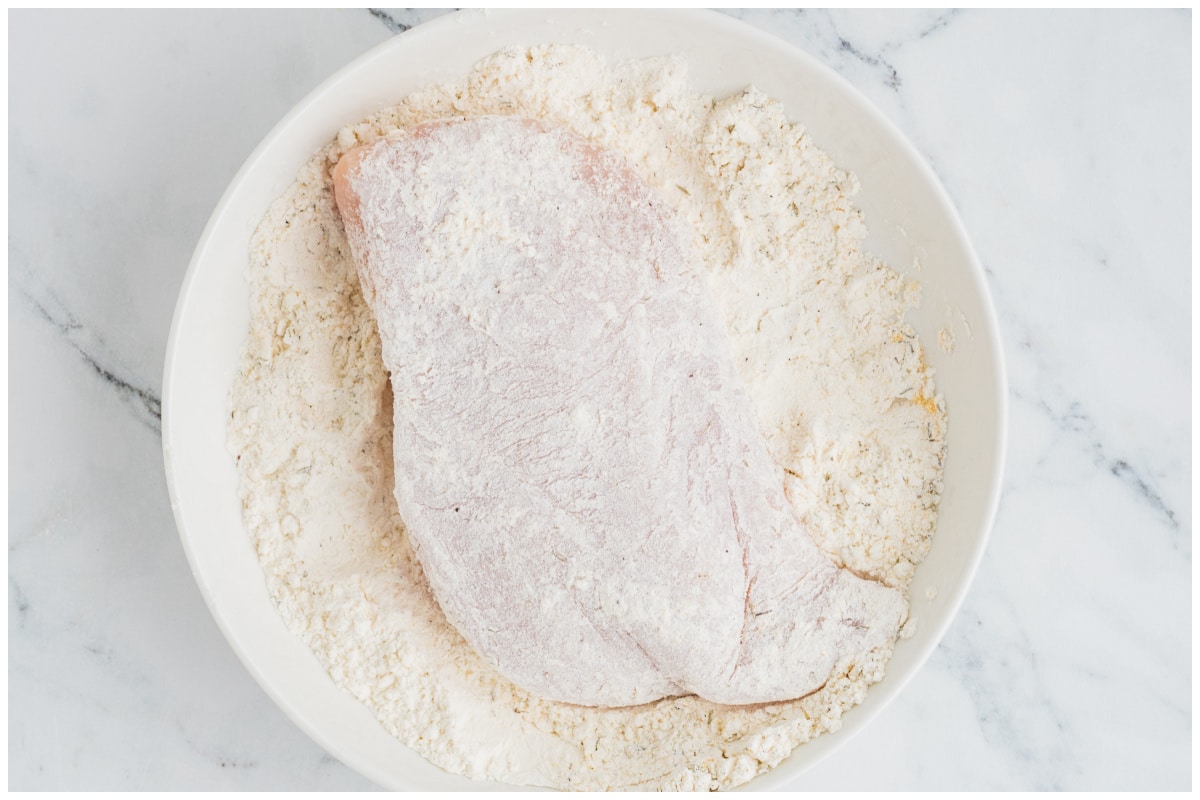 Dredging chicken in flour mixture.