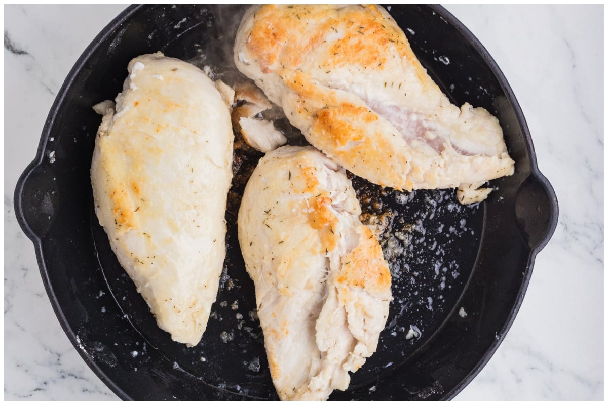 Searing chicken breast in a large skillet.