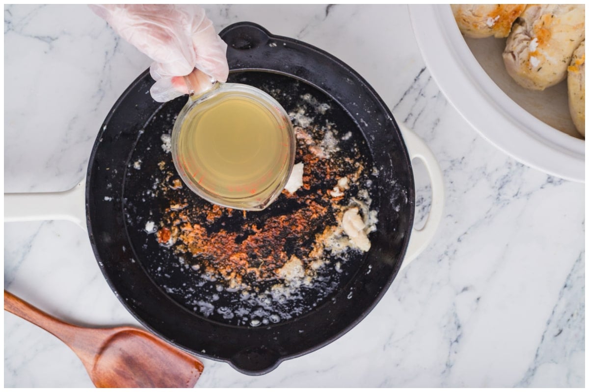 Adding broth to the skillet to make the sauce.